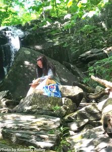 A writer sits at the base of Goodell Brook Falls.